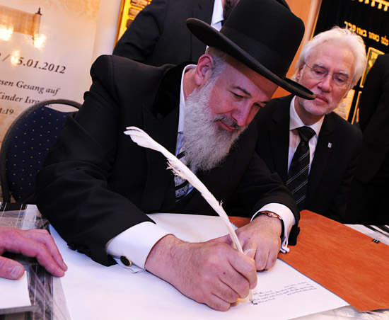 Oberrabbiner Jona Metzger, höchster Rabbiner aus Israel, schreibt den ersten Buchstaben in der neuen Torahrolle, im Hintergrund Bernd Strauch, Bürgermeister der Landeshauptstadt Hannover. (© Matthias Hinrichsen)